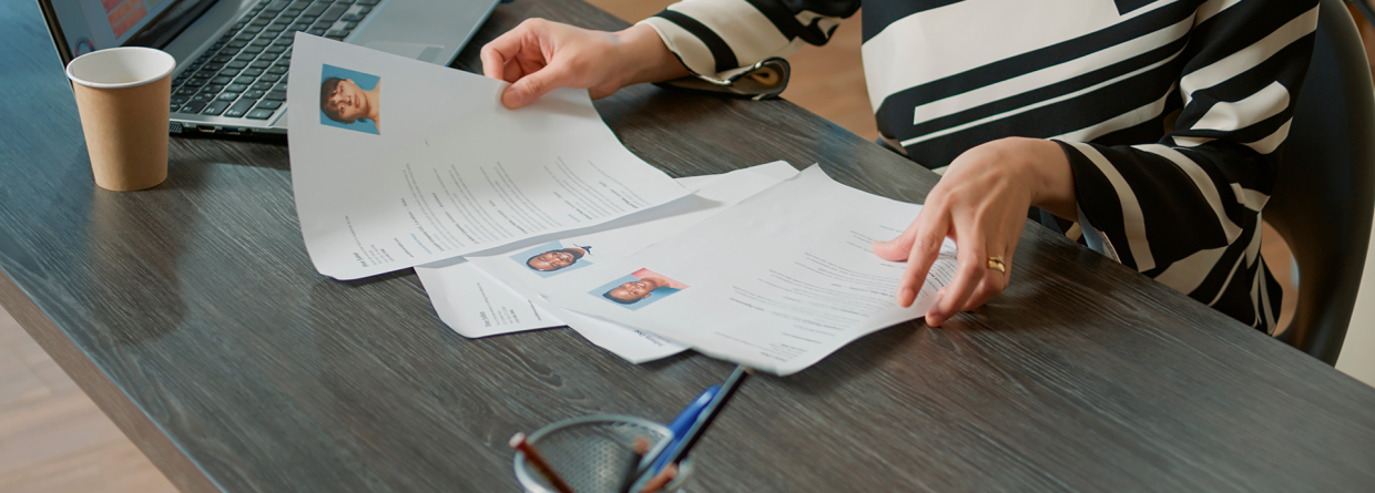 Werkgeefster bekijkt sollicitatiebrieven achter bureau met laptop